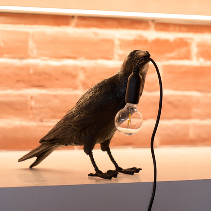 Stolní lampa s havranem držícím žárovku