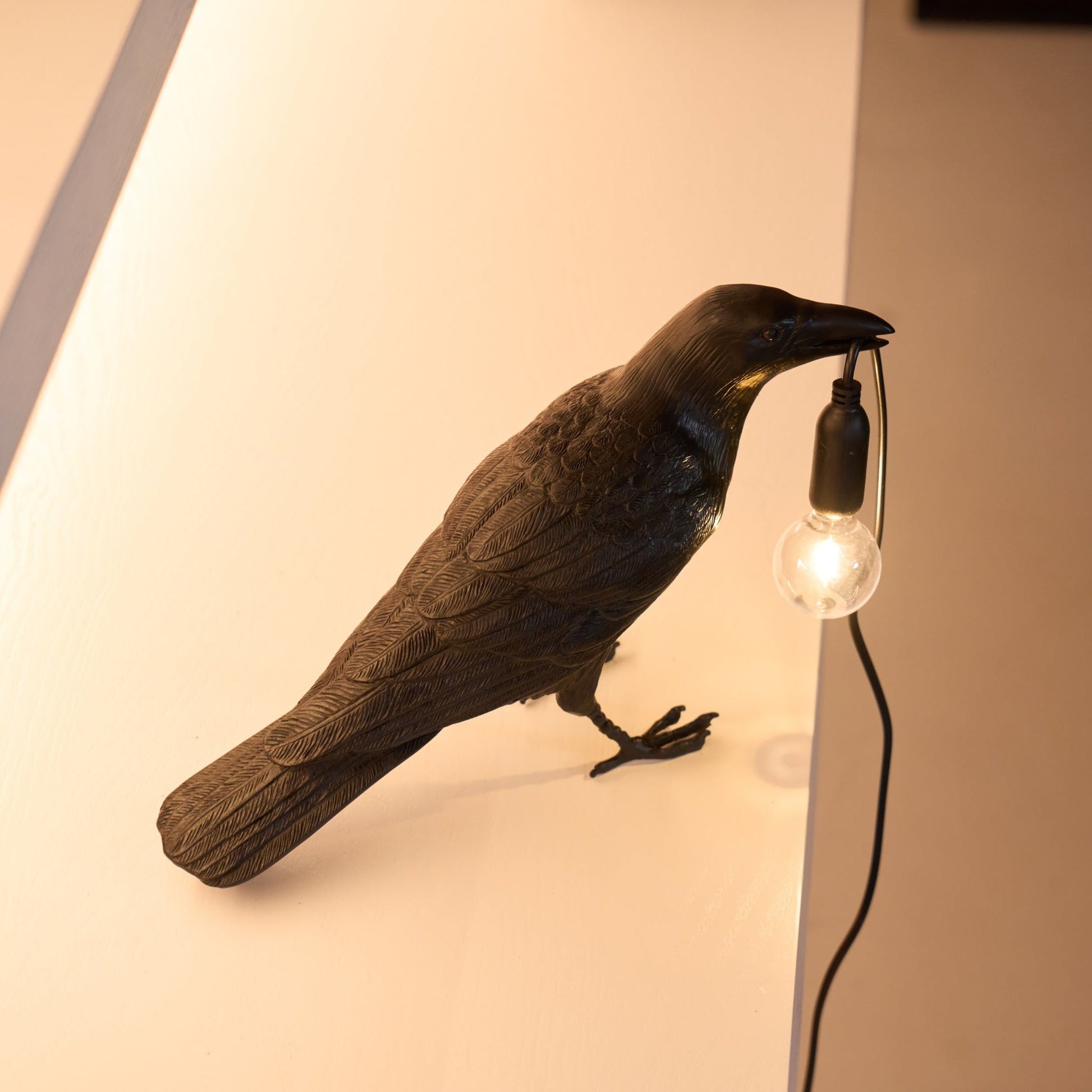 Stolní lampa s havranem držícím žárovku