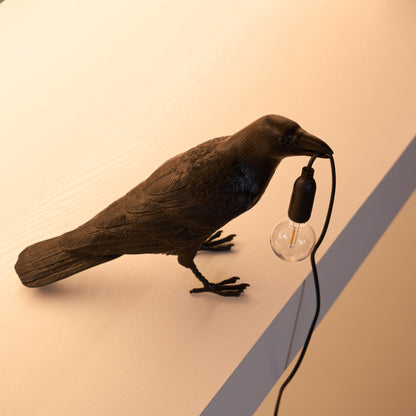 Stolní lampa s havranem držícím žárovku
