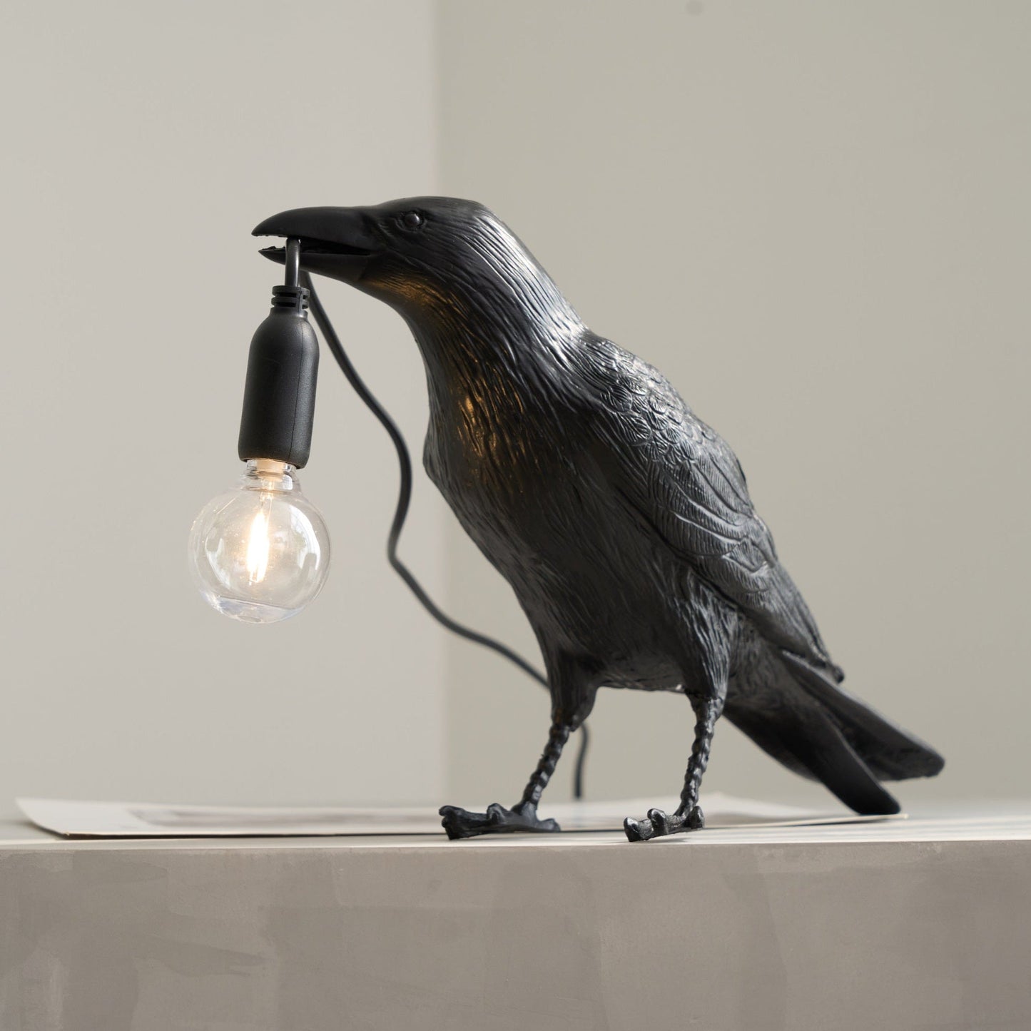 Stolní lampa s havranem držícím žárovku
