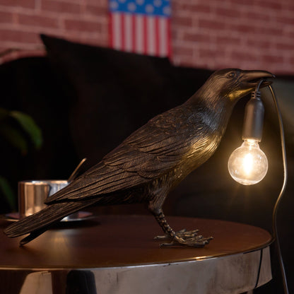 Stolní lampa s havranem držícím žárovku