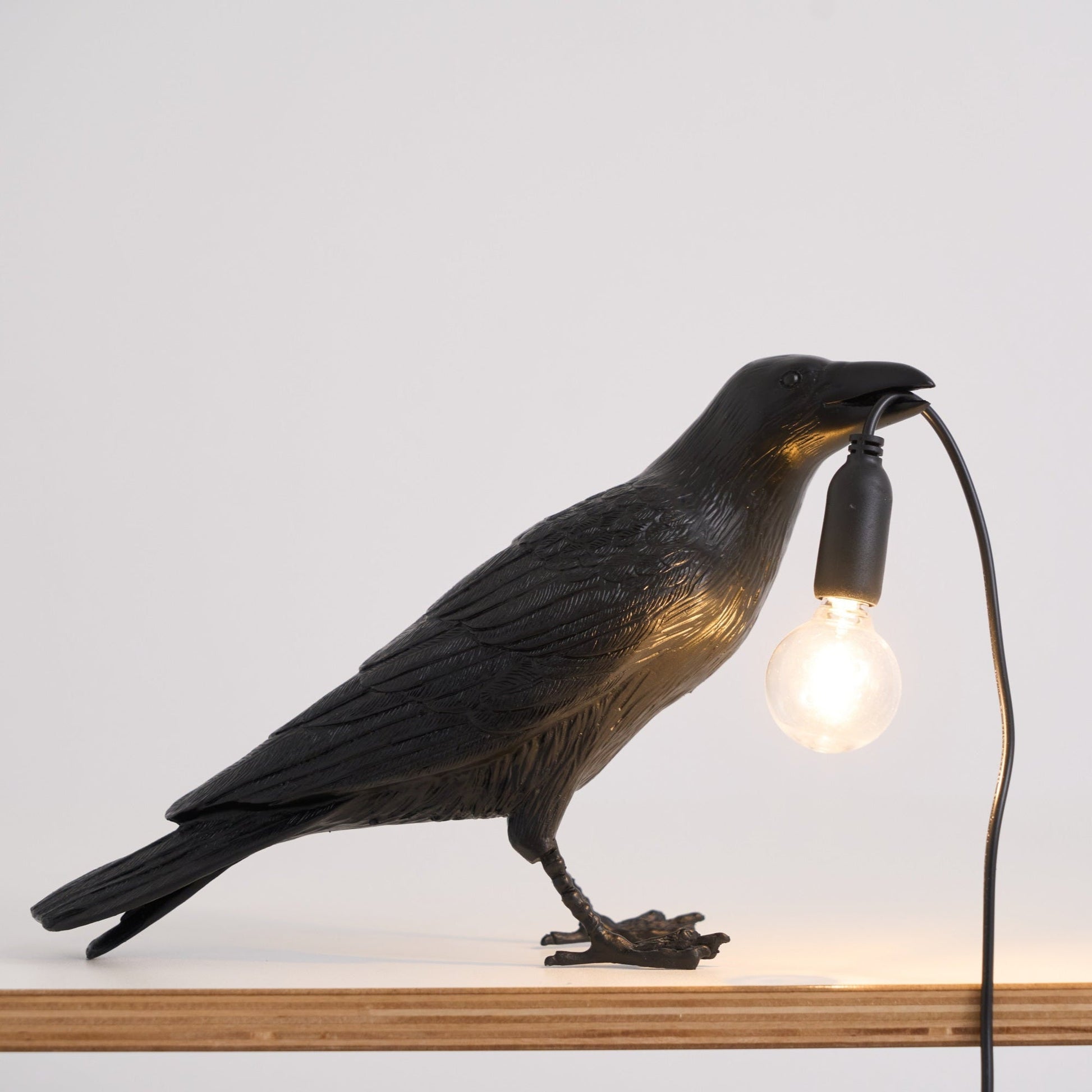 Stolní lampa s havranem držícím žárovku