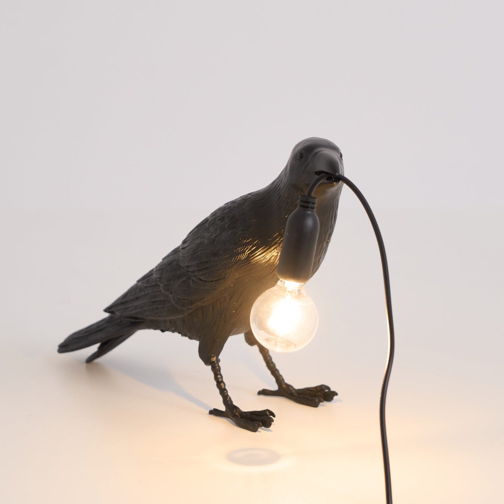 Stolní lampa s havranem držícím žárovku