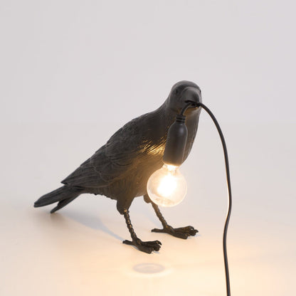Stolní lampa s havranem držícím žárovku