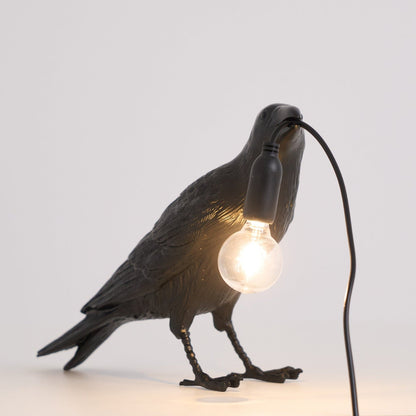 Stolní lampa s havranem držícím žárovku