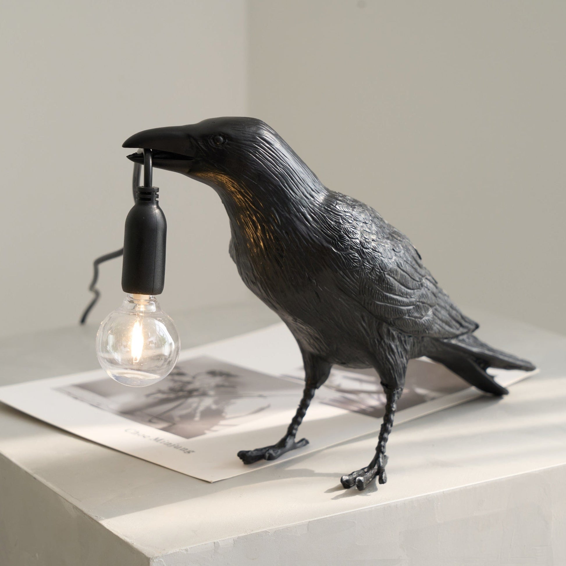Stolní lampa s havranem držícím žárovku