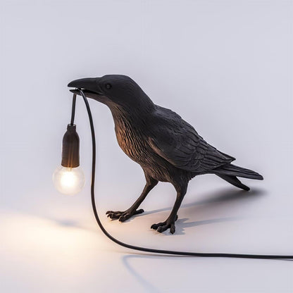 Stolní lampa s havranem držícím žárovku