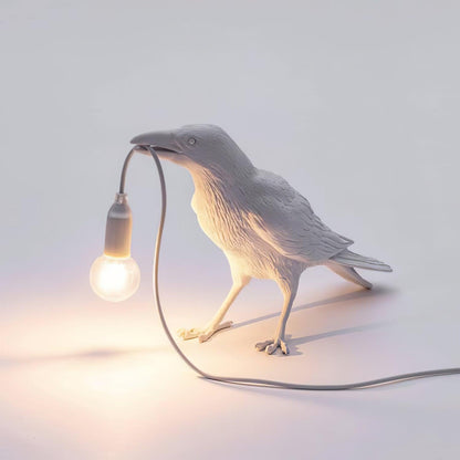 Stolní lampa s havranem držícím žárovku