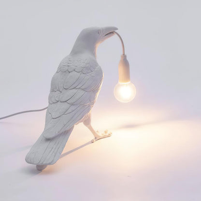 Stolní lampa s havranem držícím žárovku