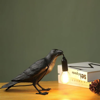 Stolní lampa s havranem držícím žárovku