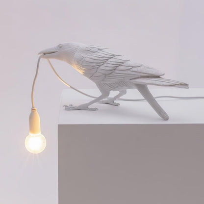 Stolní lampa s havranem držícím žárovku
