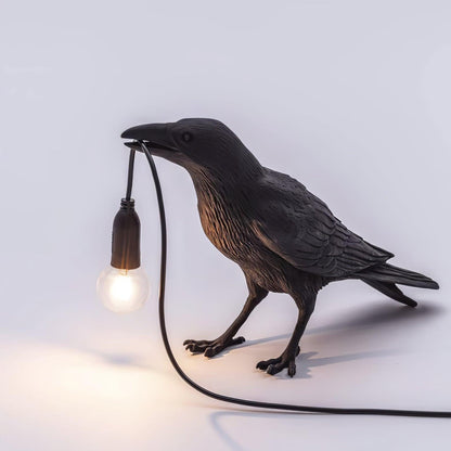 Stolní lampa s havranem držícím žárovku