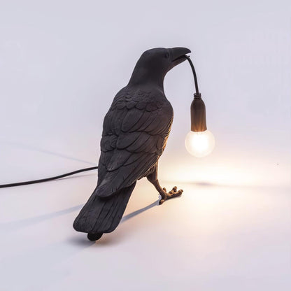 Stolní lampa s havranem držícím žárovku