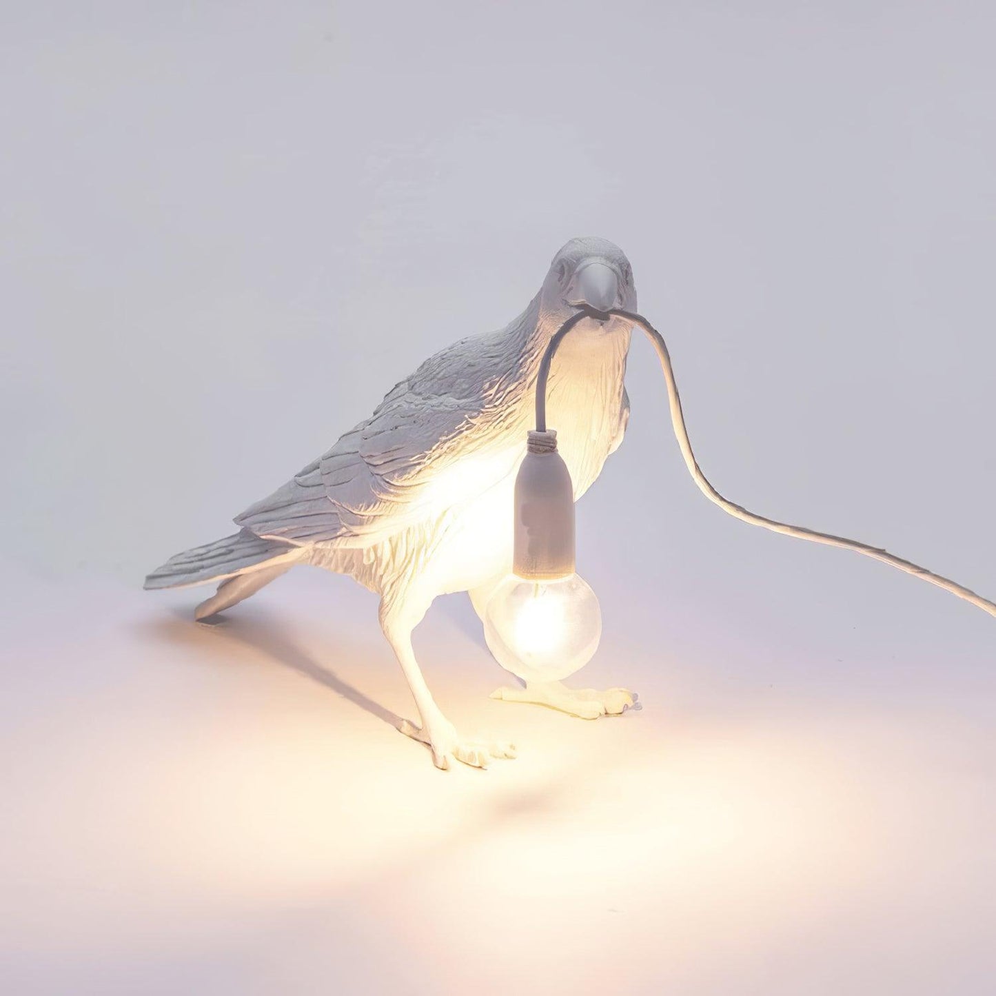 Stolní lampa s havranem držícím žárovku