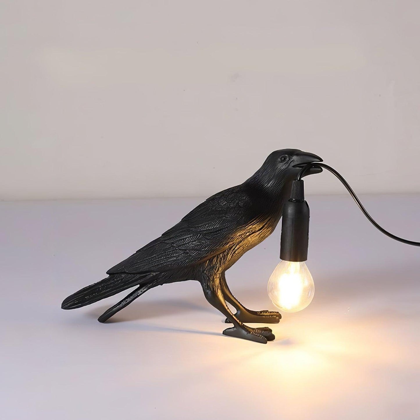 Stolní lampa s havranem držícím žárovku