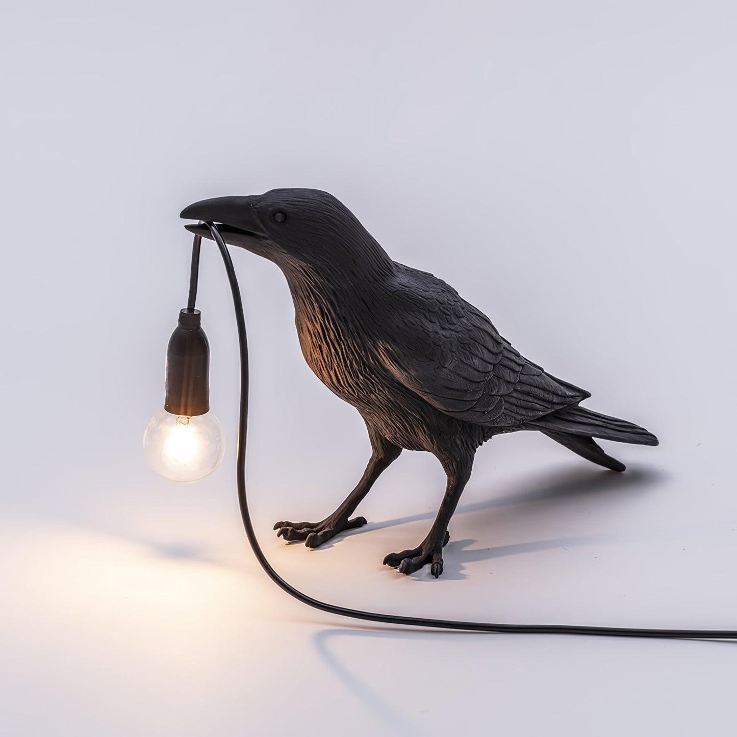 Stolní lampa s havranem držícím žárovku