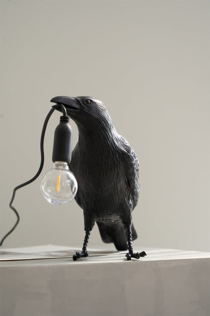 Stolní lampa s havranem držícím žárovku