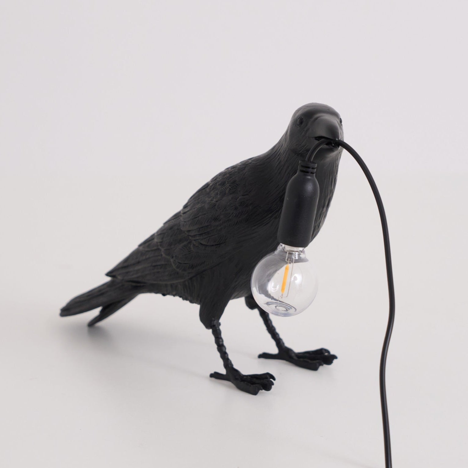 Stolní lampa s havranem držícím žárovku