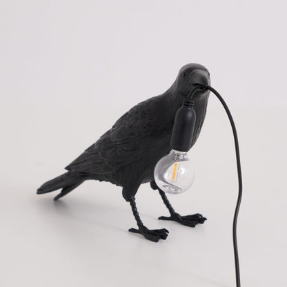Stolní lampa s havranem držícím žárovku