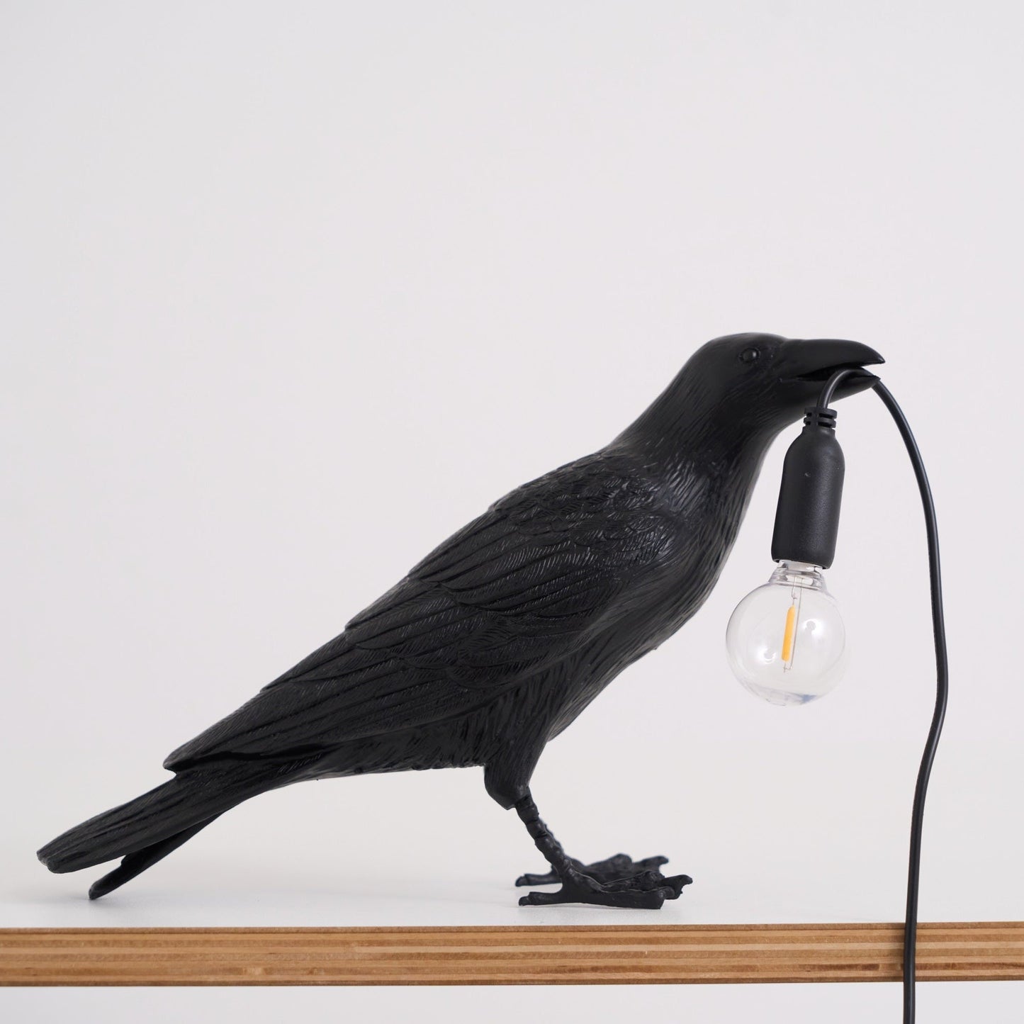 Stolní lampa s havranem držícím žárovku