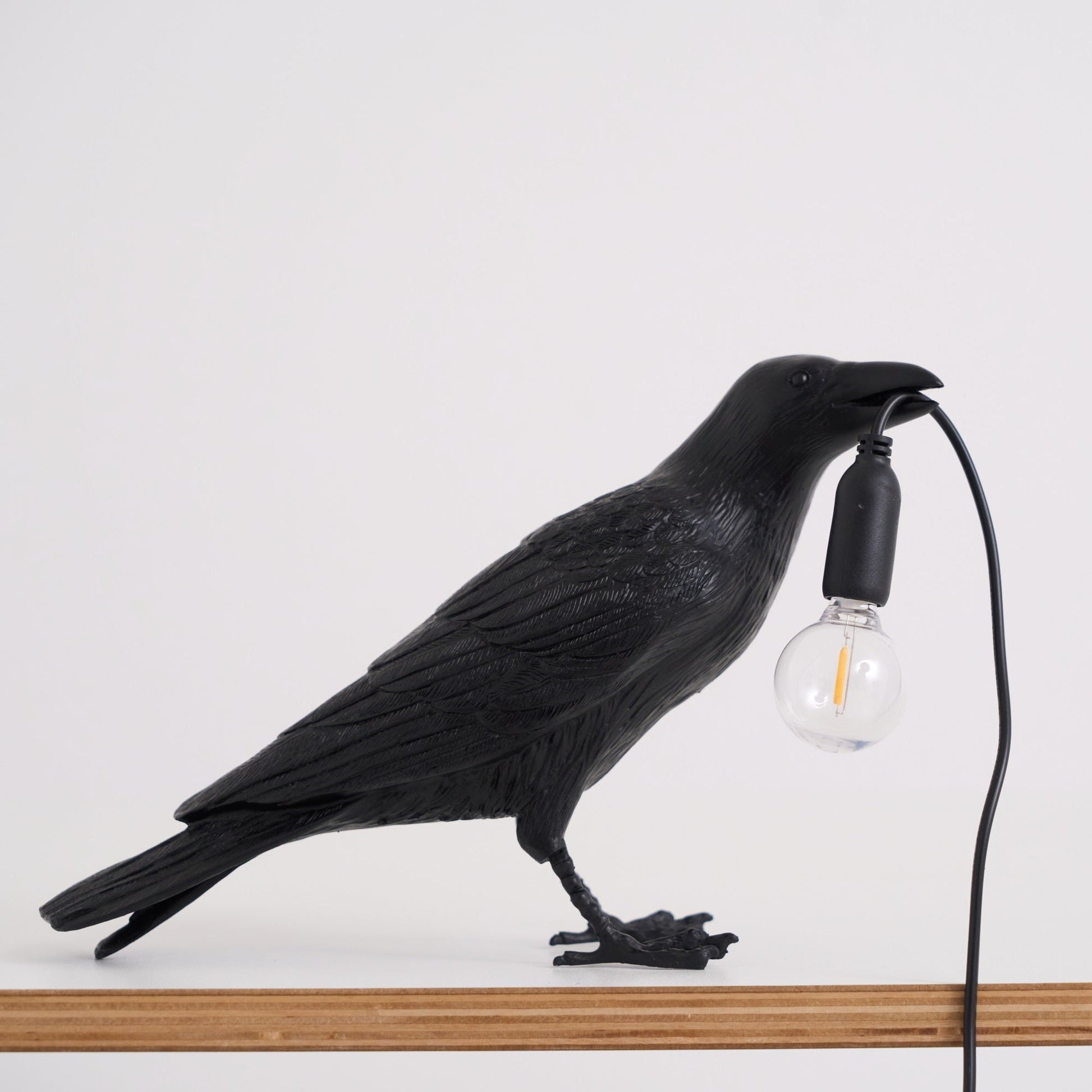 Stolní lampa s havranem držícím žárovku