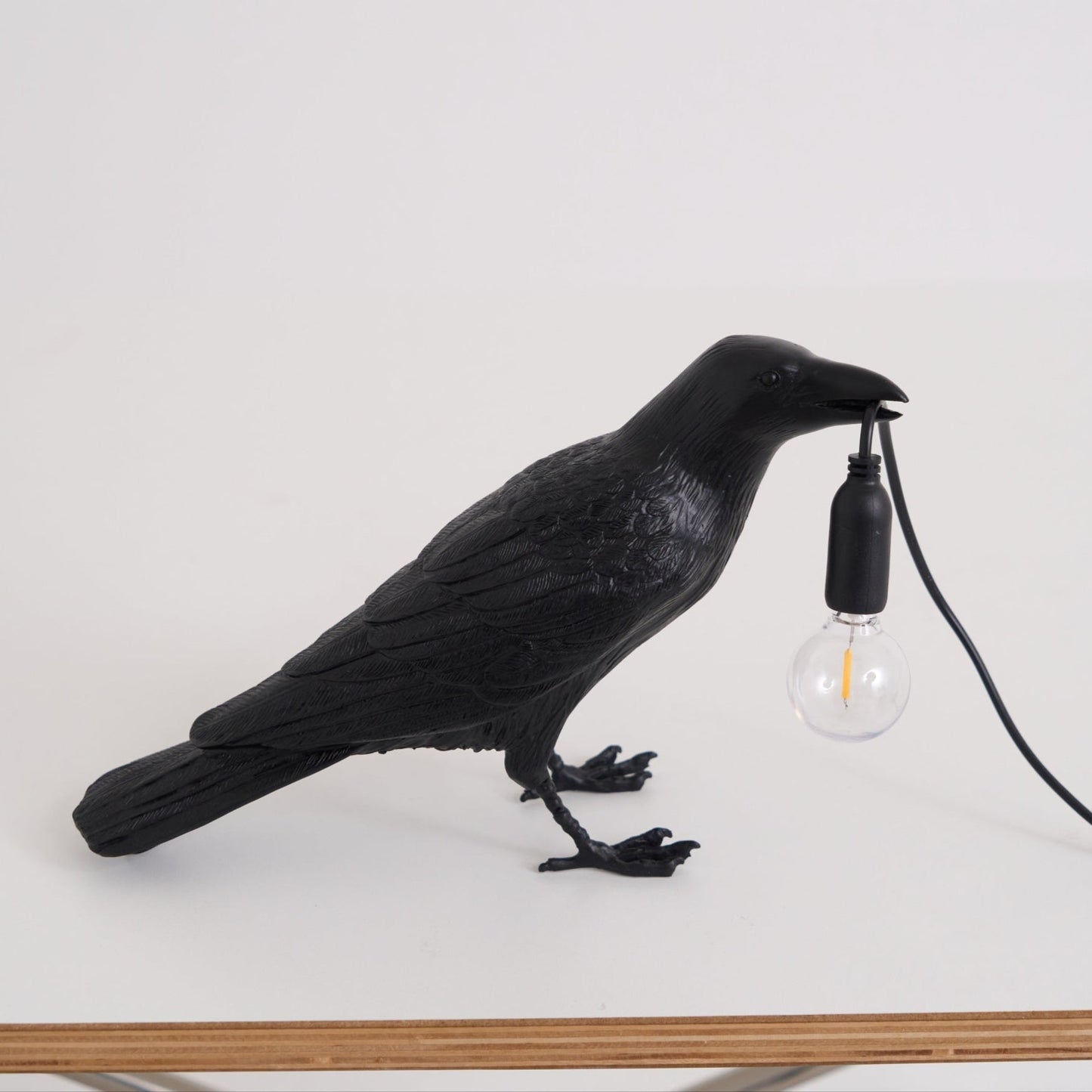 Stolní lampa s havranem držícím žárovku
