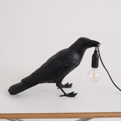 Stolní lampa s havranem držícím žárovku