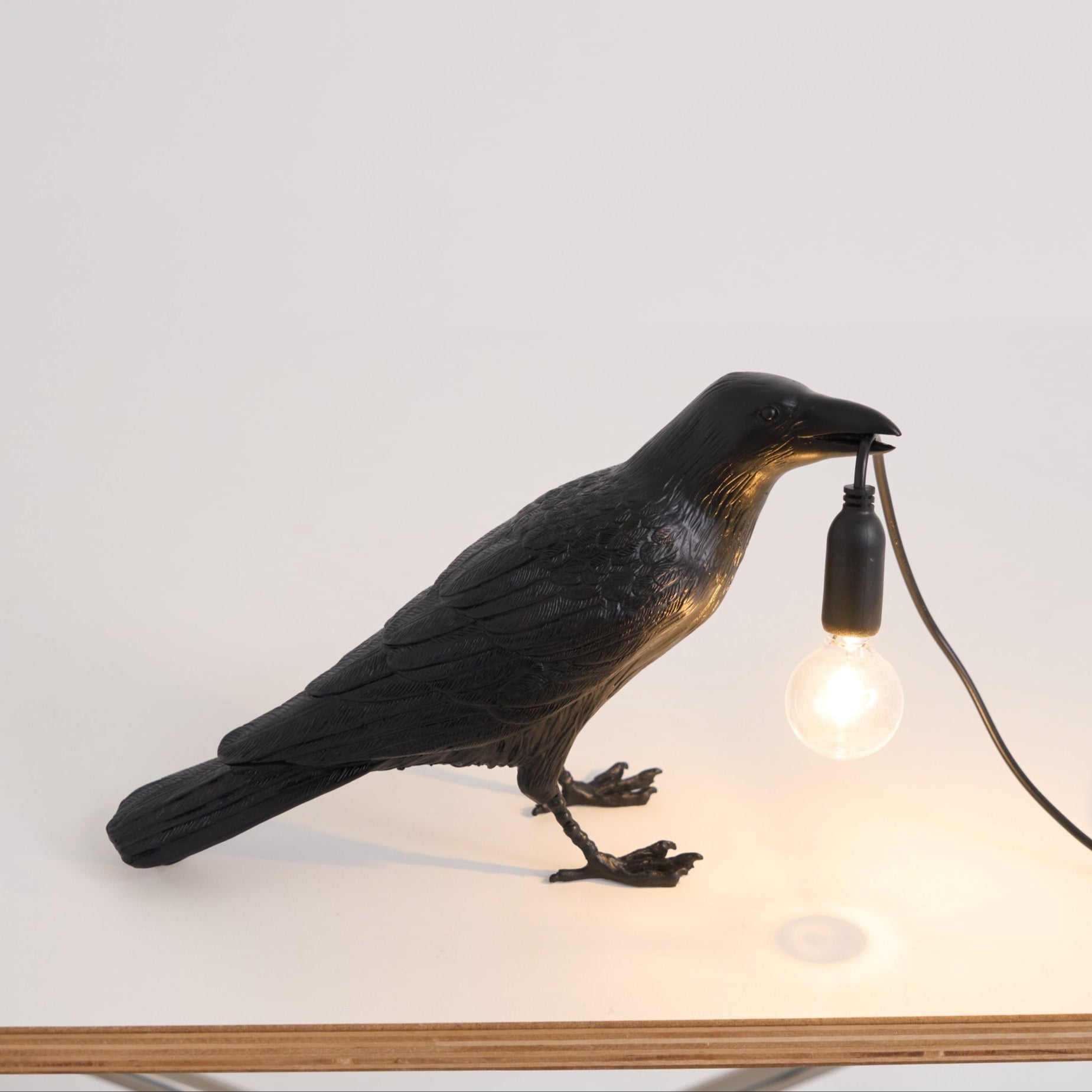 Stolní lampa s havranem držícím žárovku