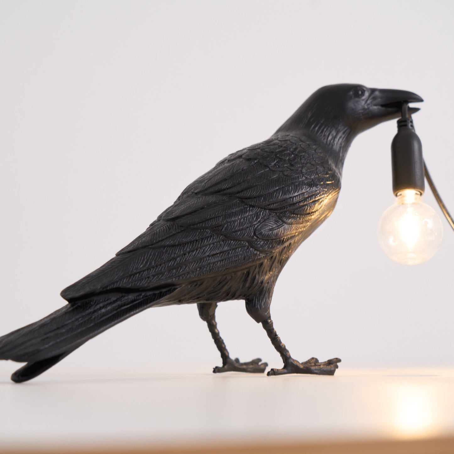 Stolní lampa s havranem držícím žárovku