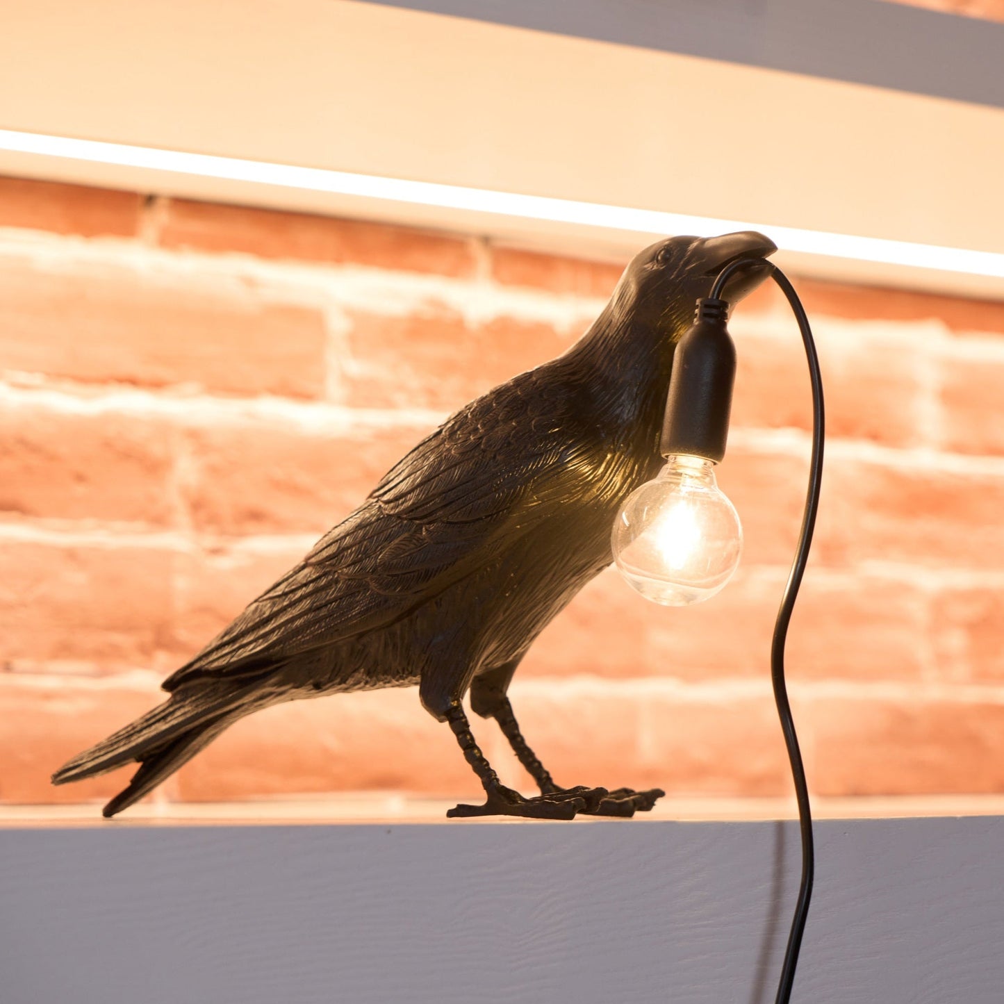 Stolní lampa s havranem držícím žárovku