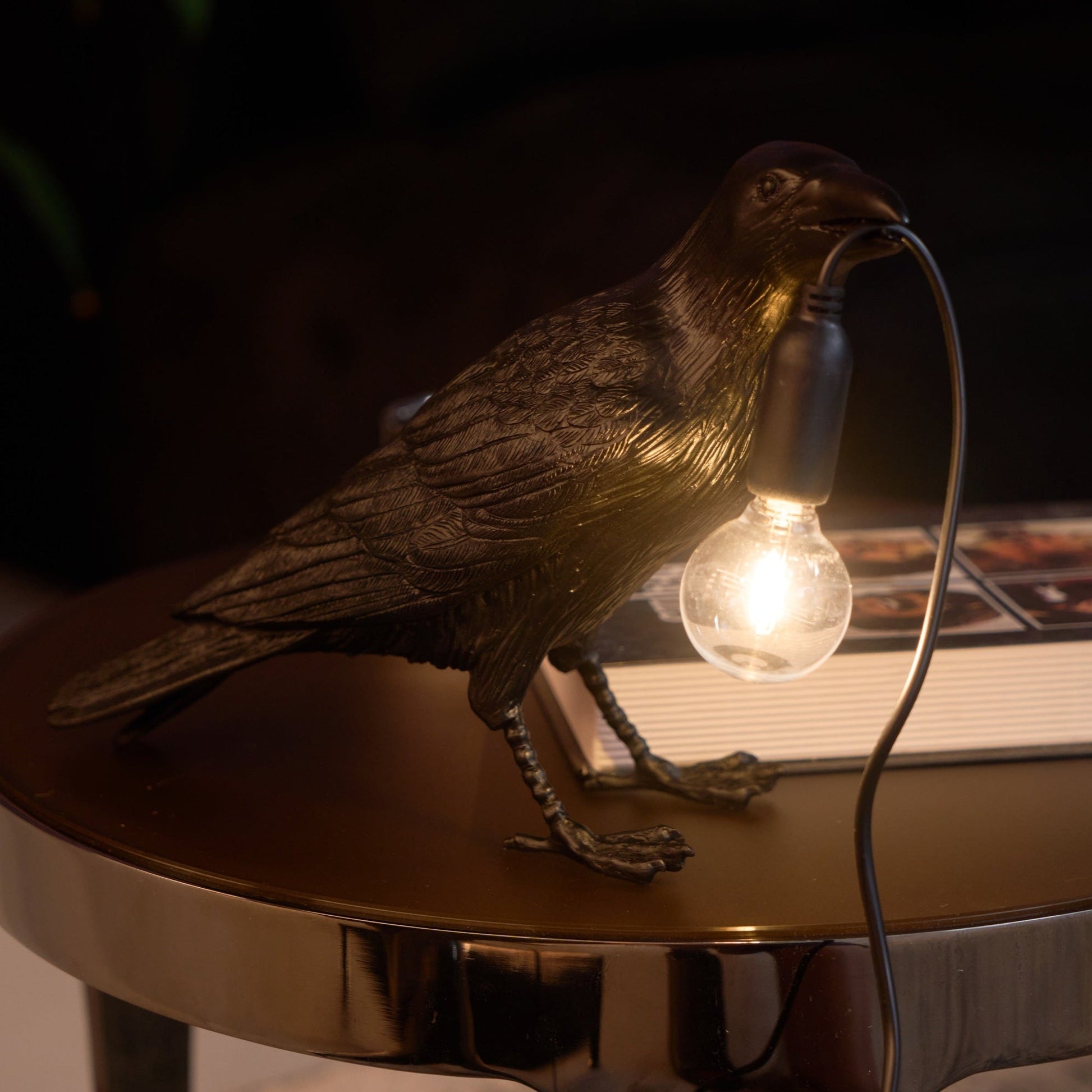 Stolní lampa s havranem držícím žárovku