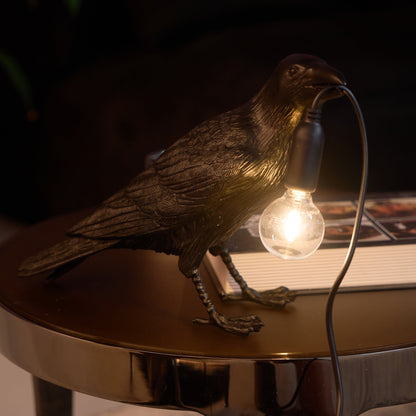 Stolní lampa s havranem držícím žárovku