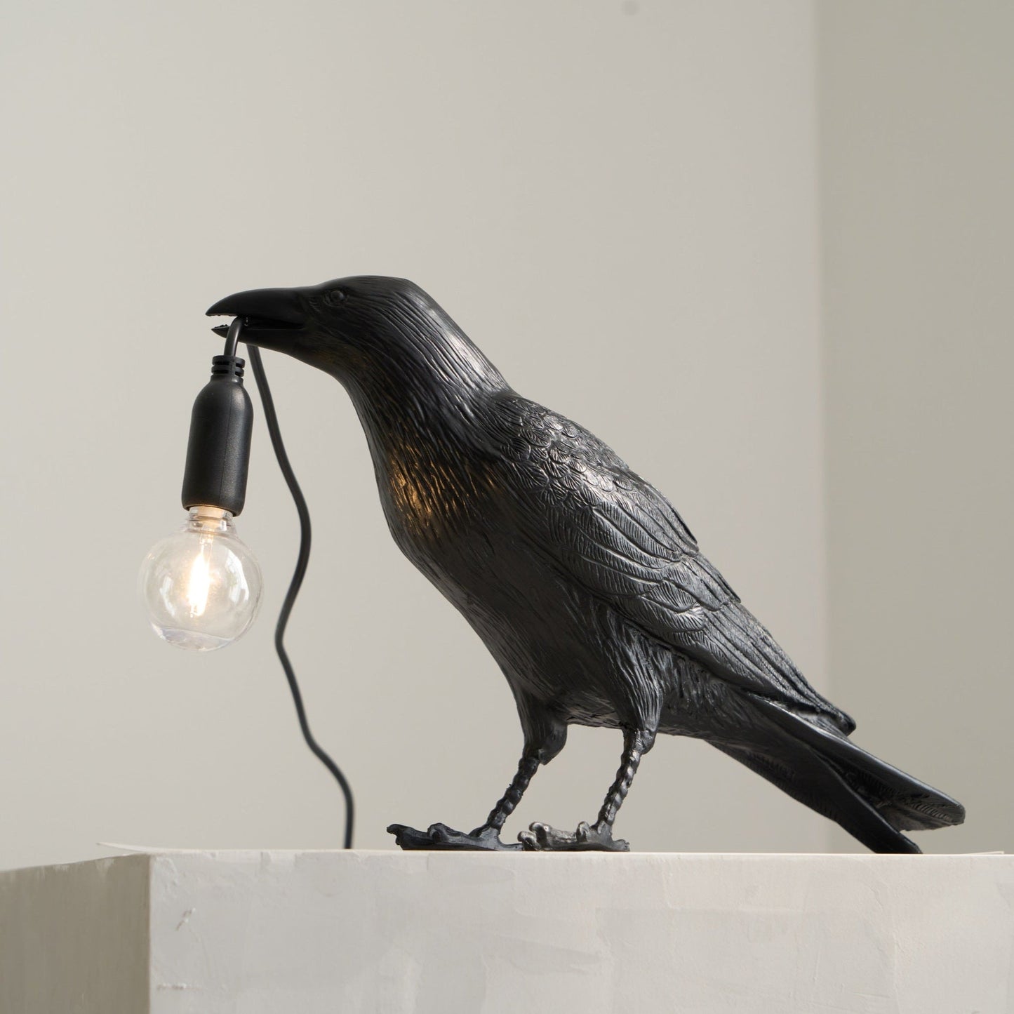 Stolní lampa s havranem držícím žárovku