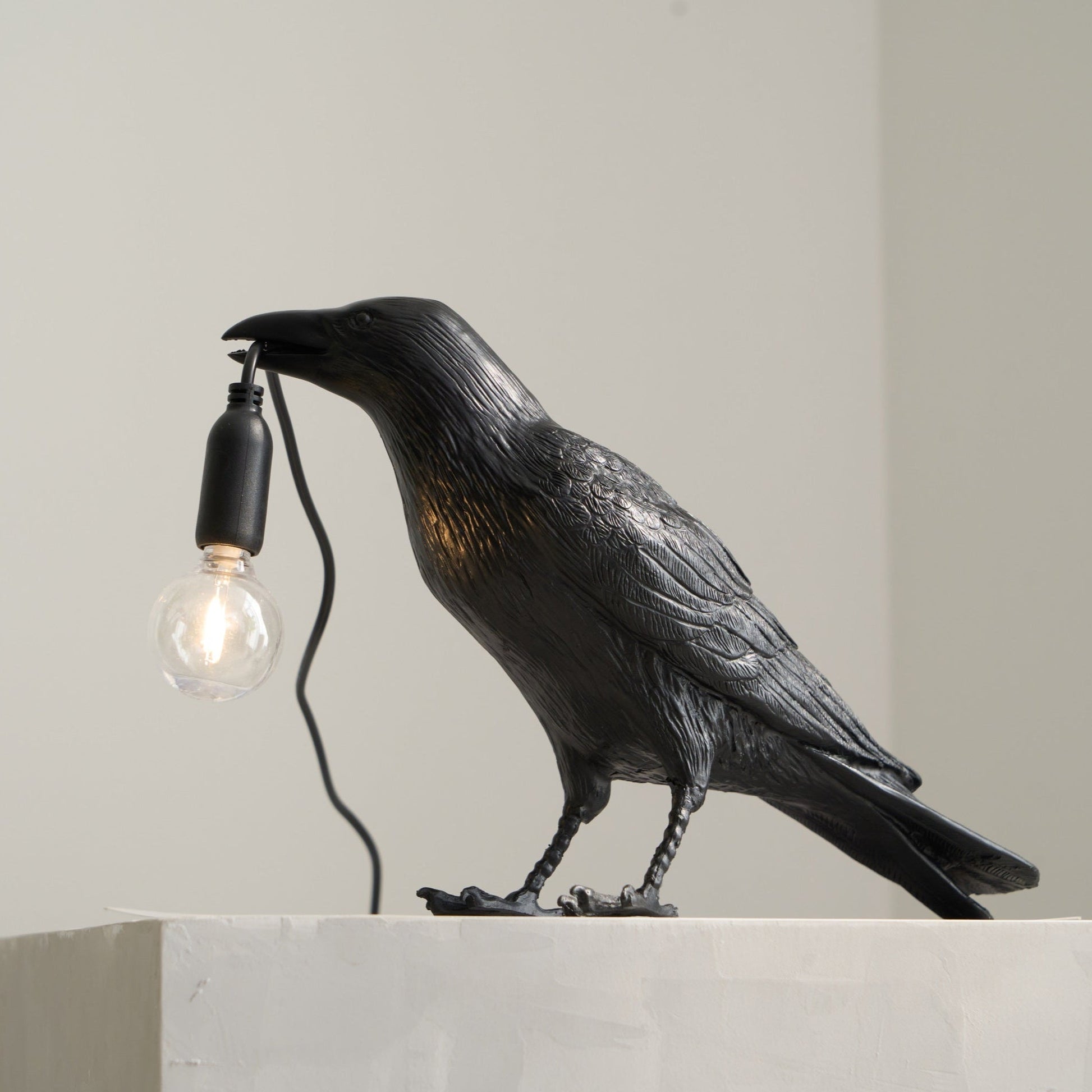 Stolní lampa s havranem držícím žárovku