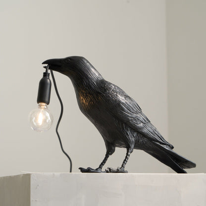 Stolní lampa s havranem držícím žárovku