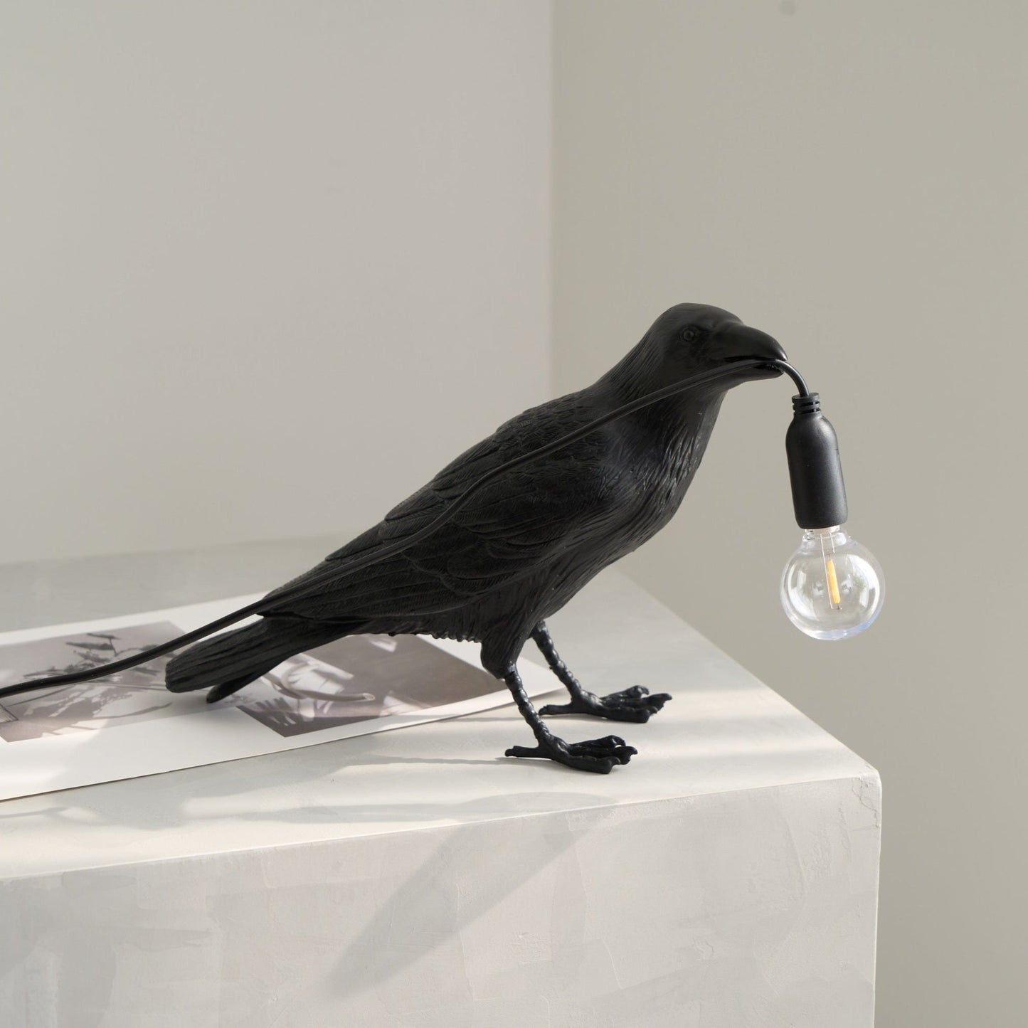 Stolní lampa s havranem držícím žárovku