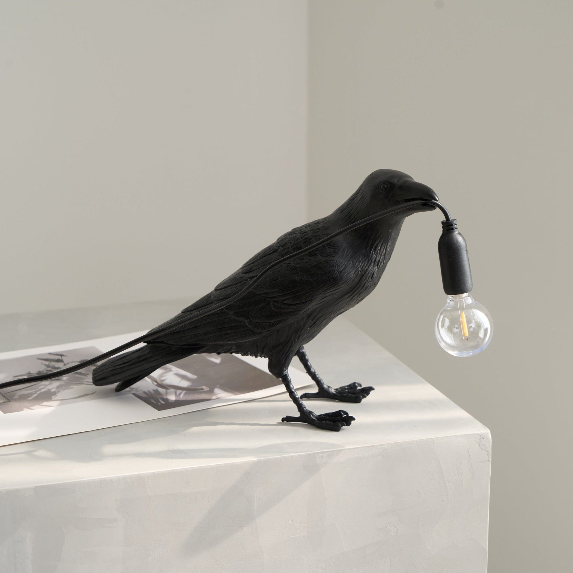 Stolní lampa s havranem držícím žárovku