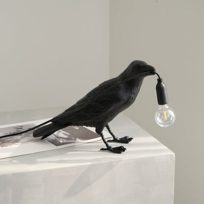 Stolní lampa s havranem držícím žárovku