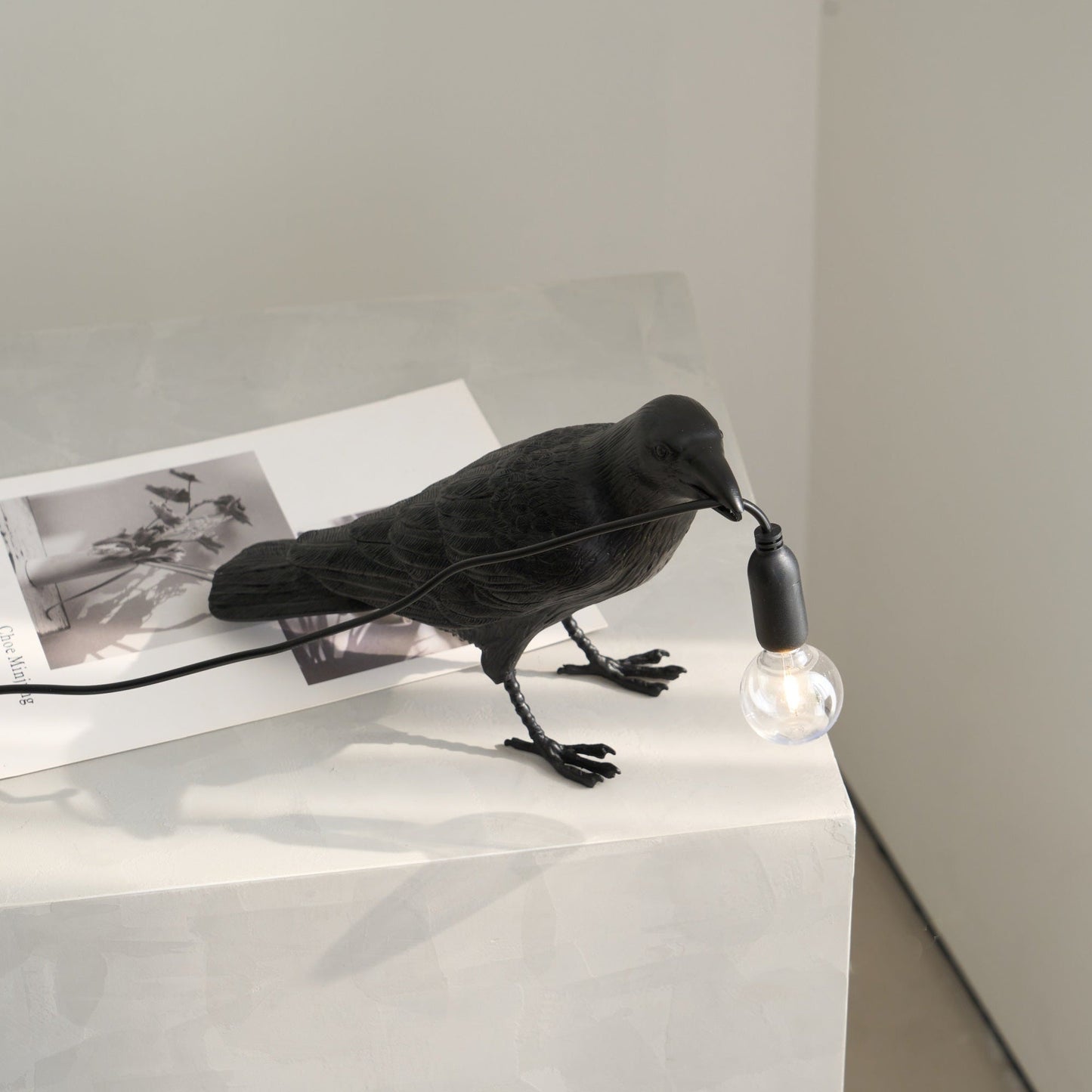 Stolní lampa s havranem držícím žárovku