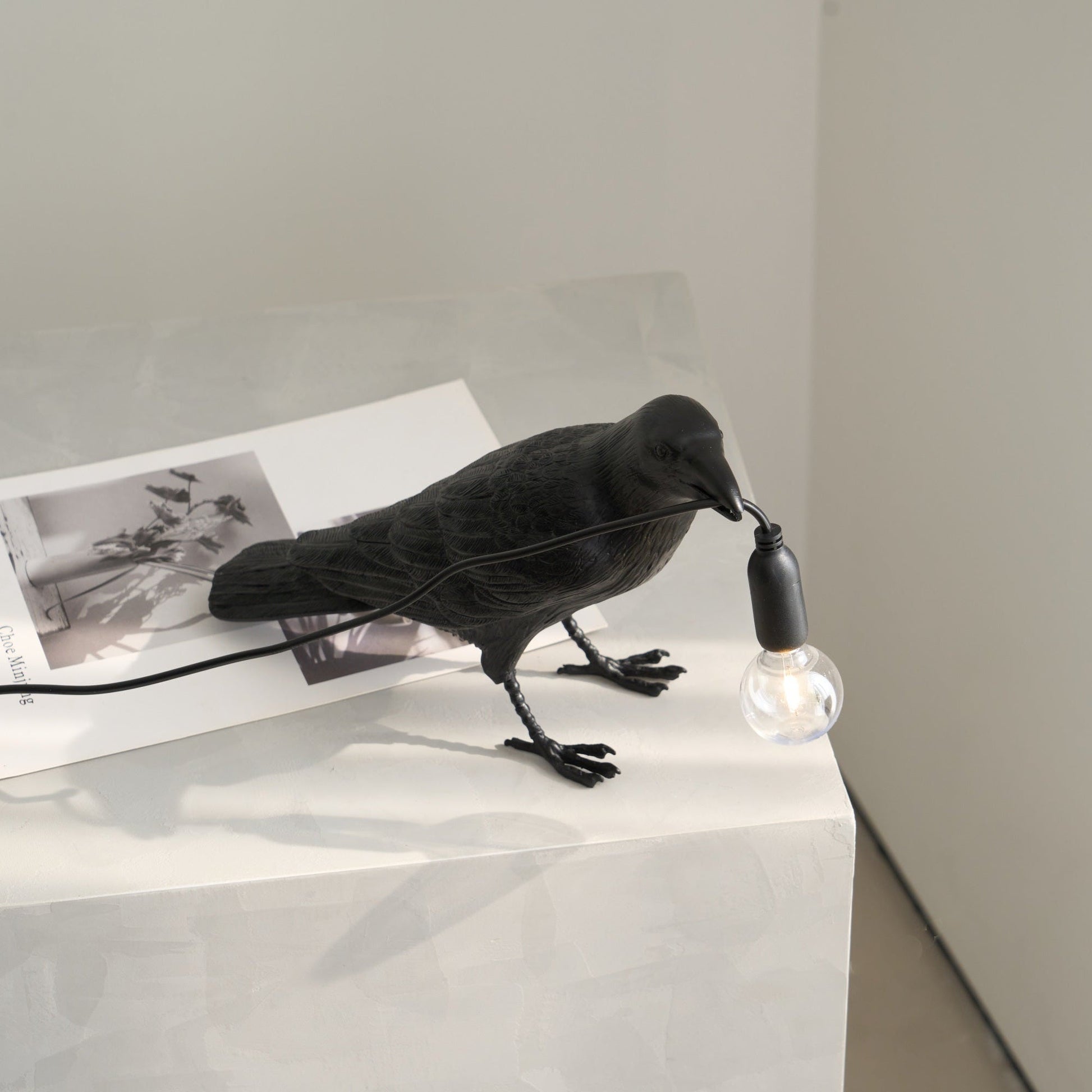Stolní lampa s havranem držícím žárovku
